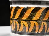 a close up of a green and yellow vase on a table