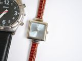 two watches sitting next to each other on a white surface