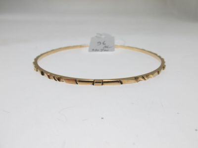 un bracelet rigide en or sur lequel est gravé le mot « love »