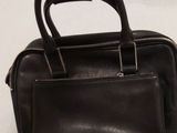 Le petit sac noir est posé sur la table, à côté d'une paire de ciseaux.