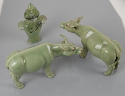 three green ceramic figurines of animals and a vase on a table