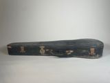 an old guitar case sitting on top of a white surface