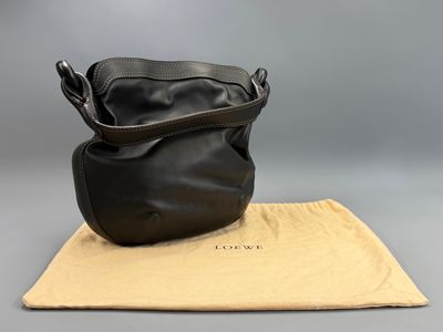 a black leather purse sitting on top of a tan cloth