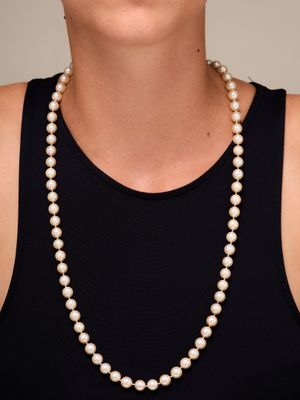 une femme portant un débardeur noir et un collier de perles