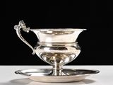 an antique silver plate with a saucer on it on a white surface