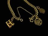 two gold necklaces with charms and a lock on a black background