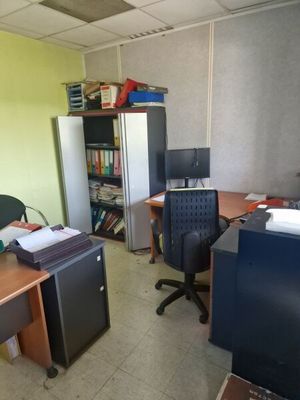 a desk with a computer and a refrigerator in a room