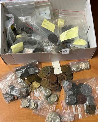 une boîte remplie de pièces posée sur une table, à côté d'une pile d'autres pièces