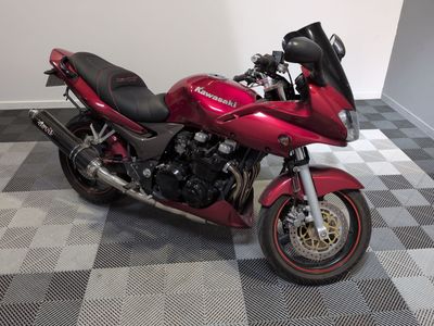 une moto rouge garée dans une pièce au sol à carreaux