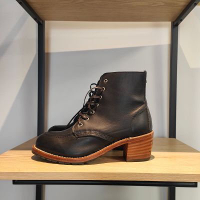 un gros plan sur une paire de bottes noires posées sur une étagère en bois