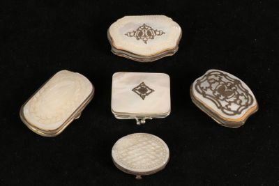 four pieces of carved ivory and silver jewelry on a black surface