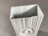 a white cup with a donut in it on a table