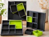 Trois boîtes noires et vertes sont posées sur une table, à côté d'une plante en pot.