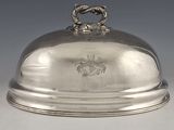 un plat ancien en argent recouvert d'un couvercle en métal orné d'un blason sur le dessus