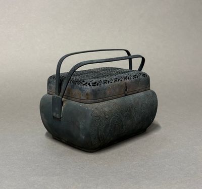 une vieille boîte en métal munie d'une poignée, posée sur une surface grise