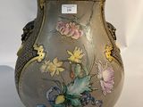 un vase orné de fleurs peintes, posé sur une surface blanche