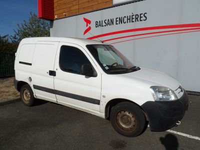 La camionnette blanche est garée devant un immeuble sur lequel est accrochée une pancarte « balcon encheres ».