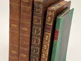 several old books are stacked on top of each other on a white surface