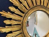 a gold sunburst mirror hanging on a blue wall