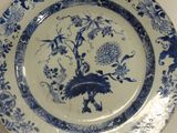 a blue and white plate with a bird and flowers on it