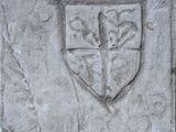 a stone plaque with a coat of arms and a cross on it