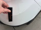 a person holding a remote control on the hood of a car