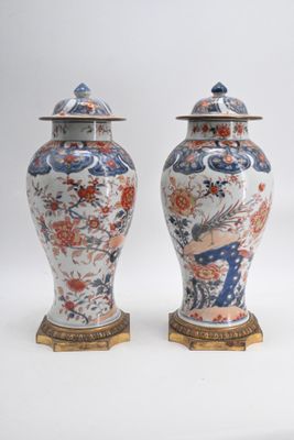 deux vases munis d'un couvercle sont posés côte à côte sur une surface blanche