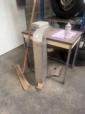 a pile of books and a broom on a table in a garage