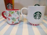 two starbucks mugs sitting on a table next to each other