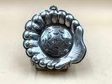 assiette en argent sur laquelle figure une main tenant un globe terrestre