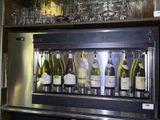 bottles of wine are lined up behind a wine cooler in a bar