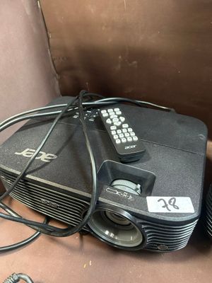 un projecteur avec une télécommande et d'autres appareils électroniques posés sur la table