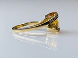 yellow sapphire and diamond ring on a white surface with reflection