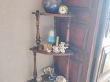 une étagère d'angle, placée dans un coin de la pièce, sur laquelle sont posées des tasses à thé et leurs soucoupes