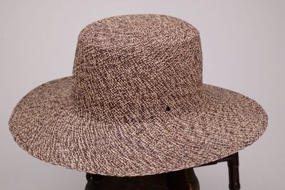une image représentant un chapeau marron posé sur une chaise