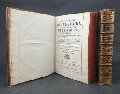 an open book with two books on top of it on a table
