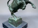 bronze sculpture of a bull leaping over a block on a marble base