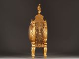 a gold clock that is sitting on a stand