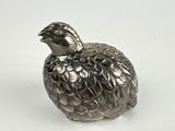 une figurine en argent représentant un oiseau sur un fond blanc