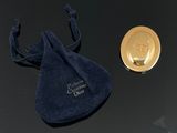 une pièce d'or et un sac en velours bleu posés sur une table