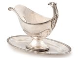 an antique silver gravy on a tray with a bird on it