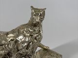 a silver statue of a cat sitting on top of a wooden block