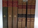 six vieux livres sont alignés sur une surface blanche