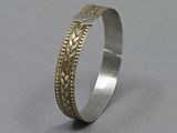 a close up of a silver bracelet with a gold band