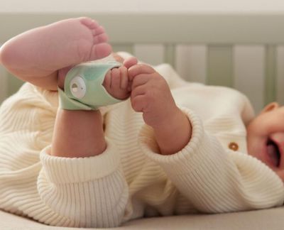 un bébé allongé dans un berceau, avec une tétine accrochée à son bras
