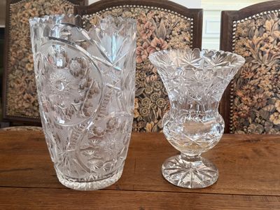 two glass vases sitting on a table in front of a chair