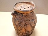 un vase marron posé sur une table, muni d'un couvercle
