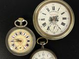 trois types différents de montres de poche posées sur une surface noire