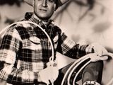 black and white photo of a man in a cowboy outfit holding a rope