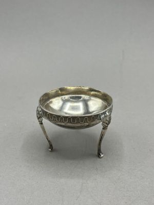an antique silver plate on a stand on a gray surface